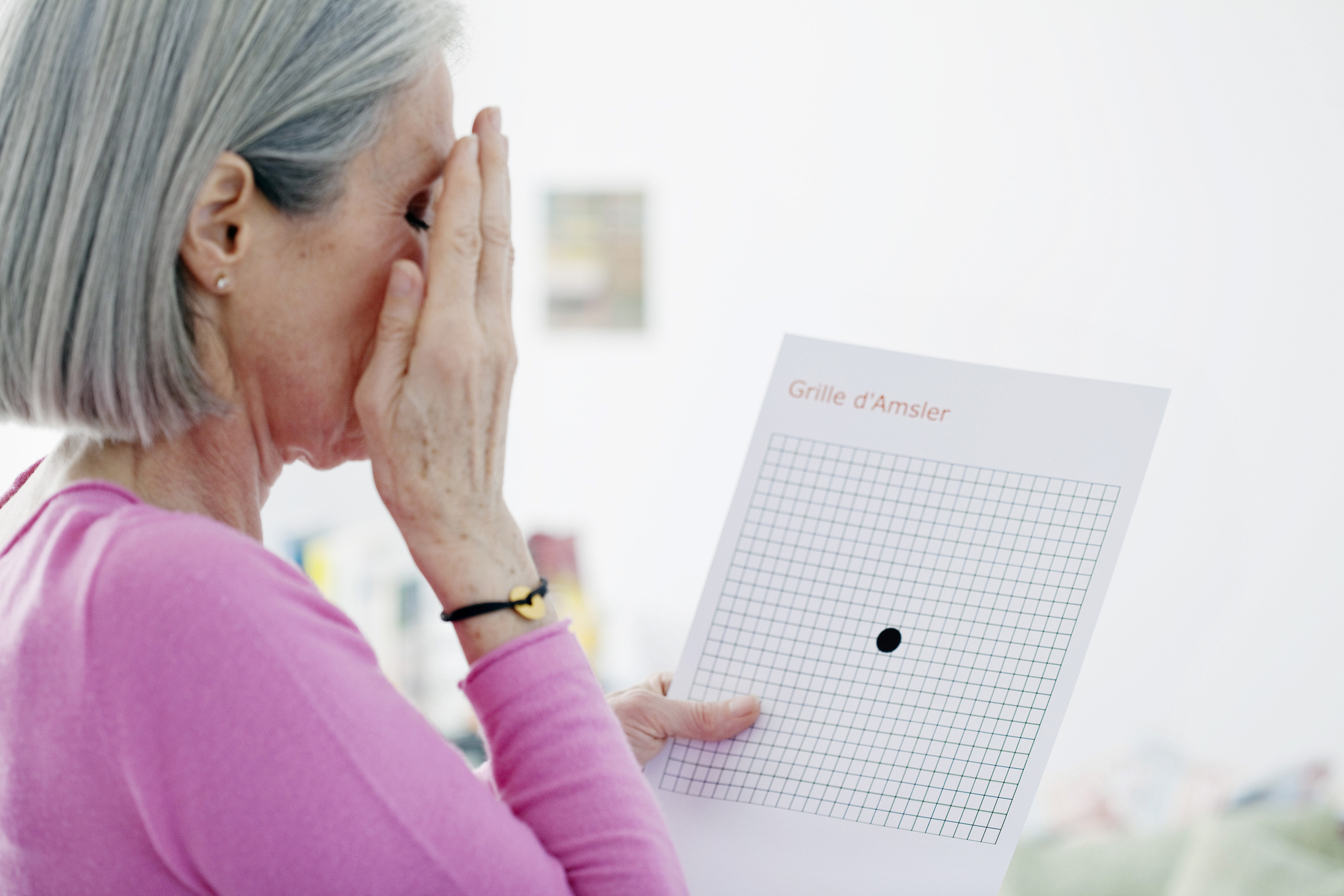 Older woman undergoing amsler grid as a way of diagnosing amd